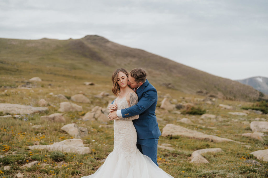 groom kissing his bride's neck during their portrait session at UTE Trailhead.